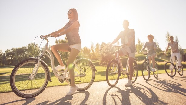 Four people riding bicycles on a paved path in a park.