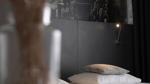 A bedroom with a bed, a nightstand, and a wall-mounted light.