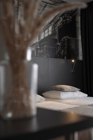 Une chambre à coucher avec un lit, une table de chevet et une lampe fixée au mur.
