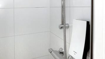A modern shower with a handheld showerhead and a wall-mounted control panel.