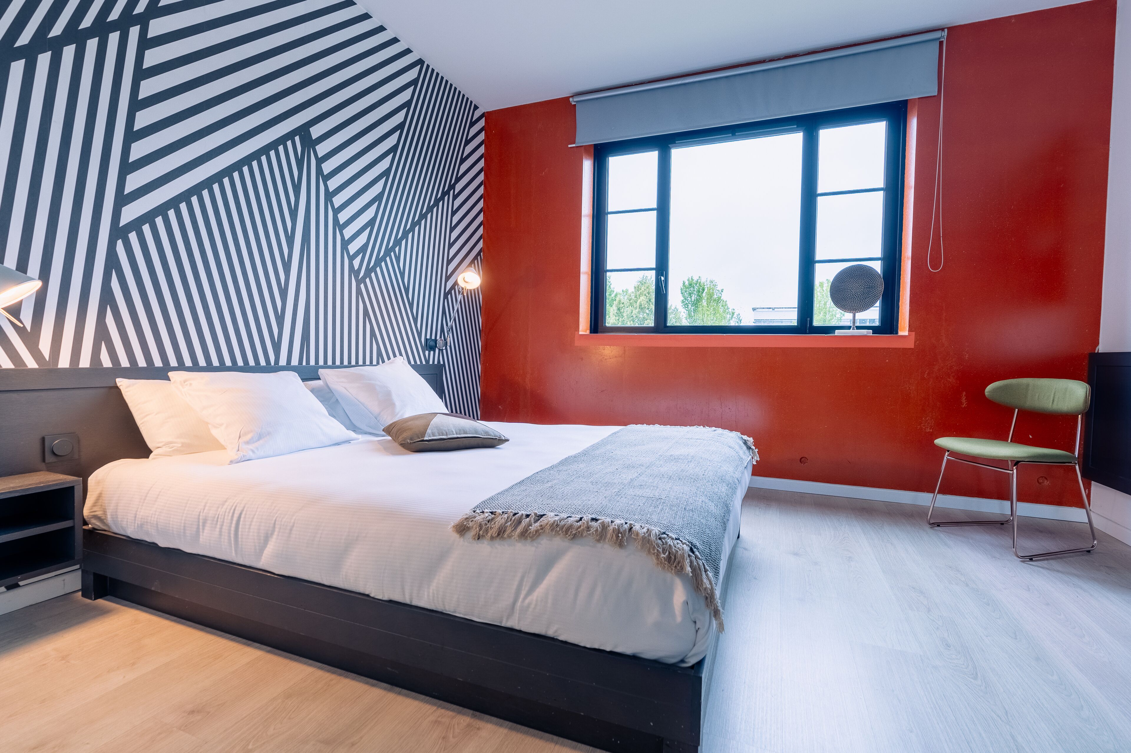 A modern bedroom with a bed, a window with a view, and a chair.