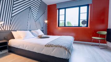 A modern bedroom with a bed, a window with a view, and a chair.