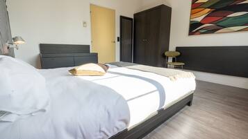 A modern bedroom with a large bed, a wardrobe, and a painting on the wall.