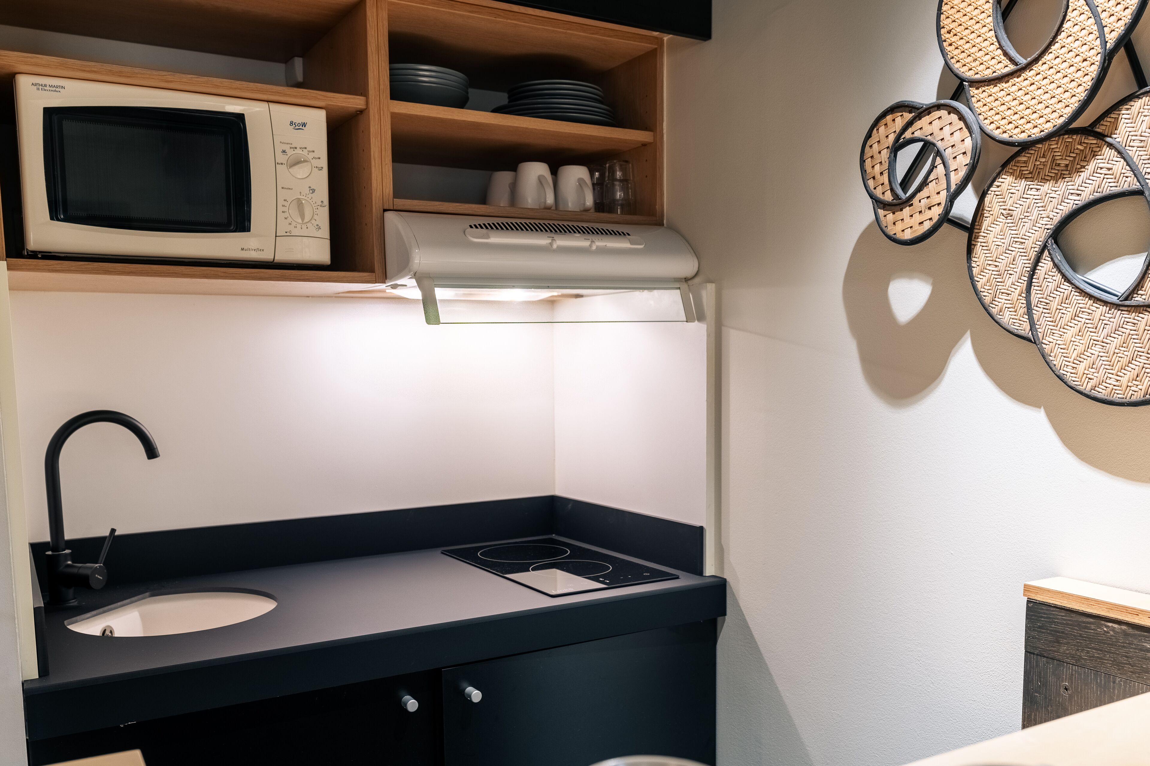 A compact kitchen with a microwave, stove, and sink.