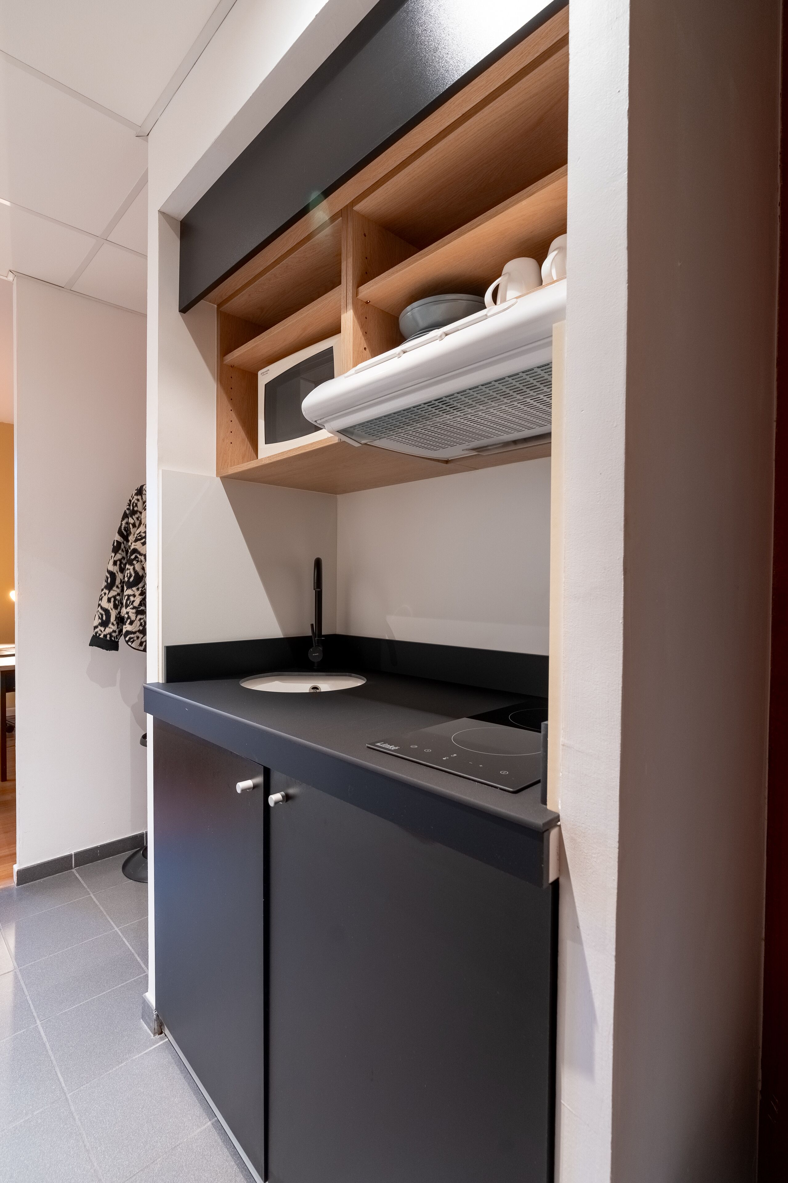 Een moderne keuken met een zwart aanrecht, een inbouwoven en een magnetron.