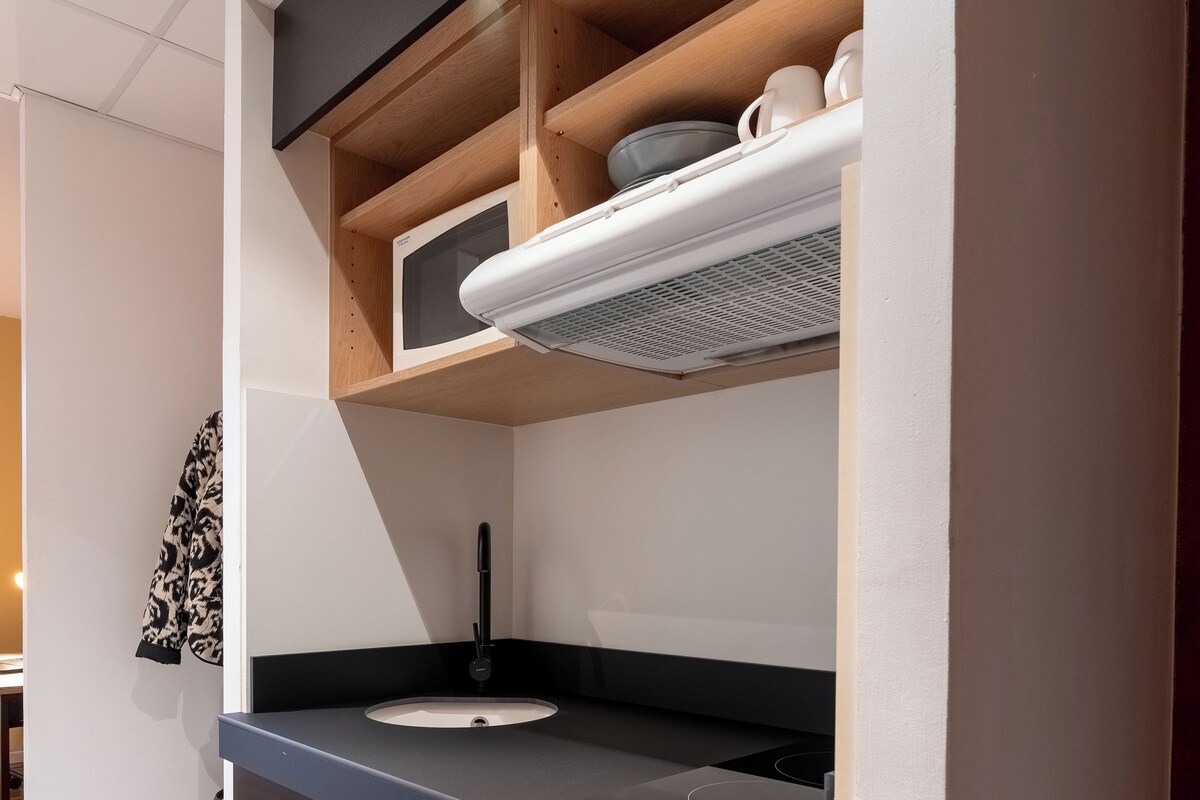 A modern kitchen with a black countertop, a built-in oven, and a microwave.