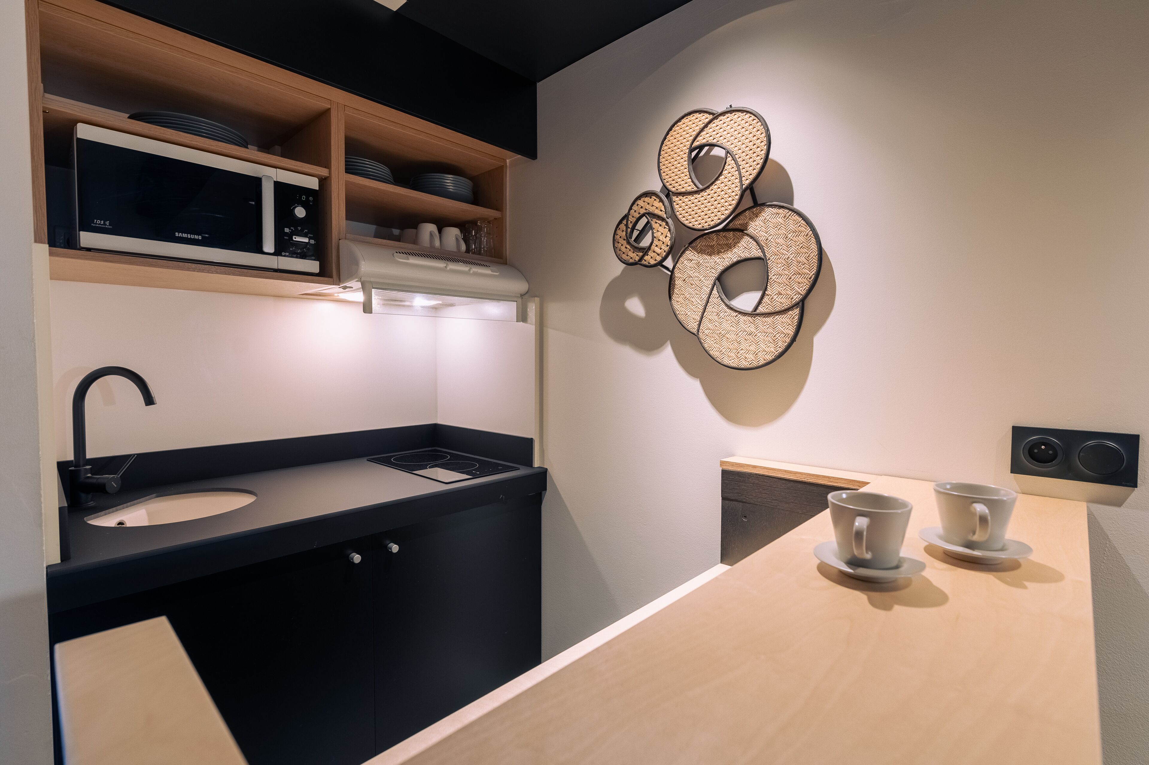 A modern kitchen with a microwave, sink, and two cups on the counter.