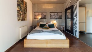 A modern bedroom with a wooden bed, two wall-mounted lamps, and a large mirror. - Cowool Lille Villeneuve D'Ascq - Ex Olivarius (Villeneuve-d'Ascq)