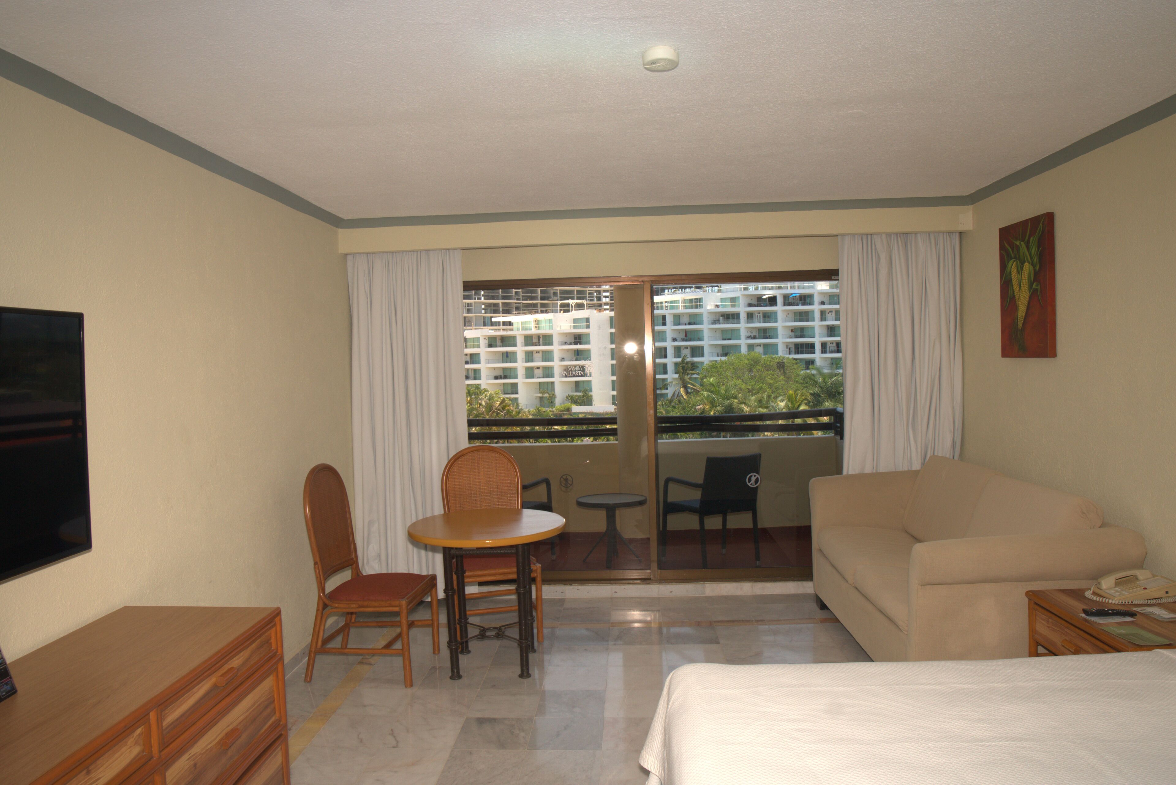 Una habitación de hotel con cama, escritorio, silla, mesa y televisor.