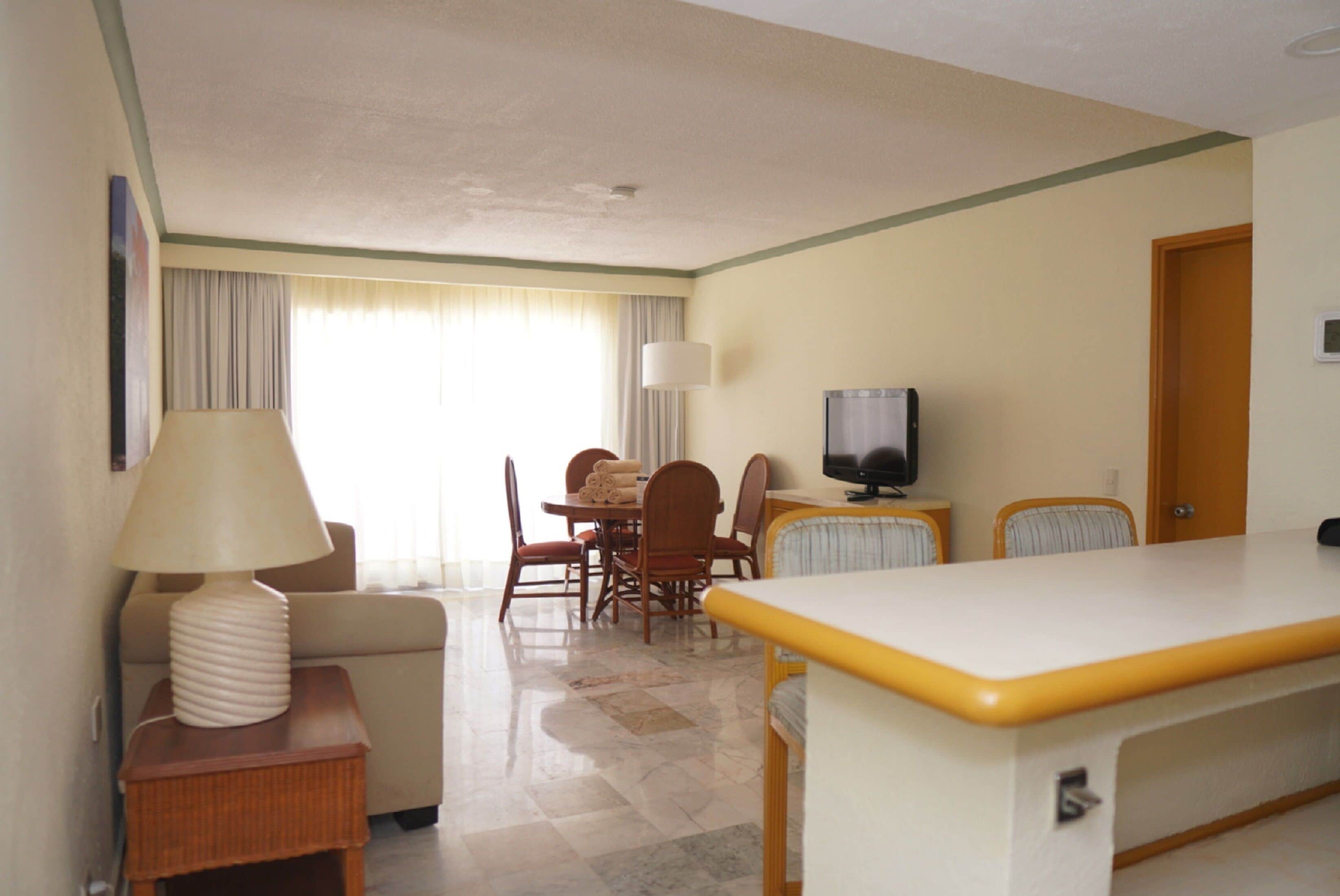 Habitación de hotel con comedor, televisión y lámpara.