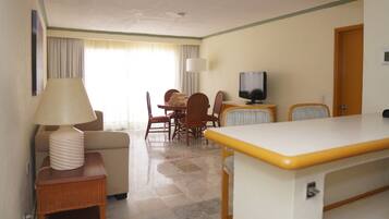Habitación de hotel con comedor, televisión y lámpara.