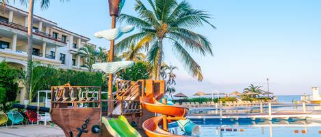 A pool area with a pirate-themed water slide and a palm tree.
