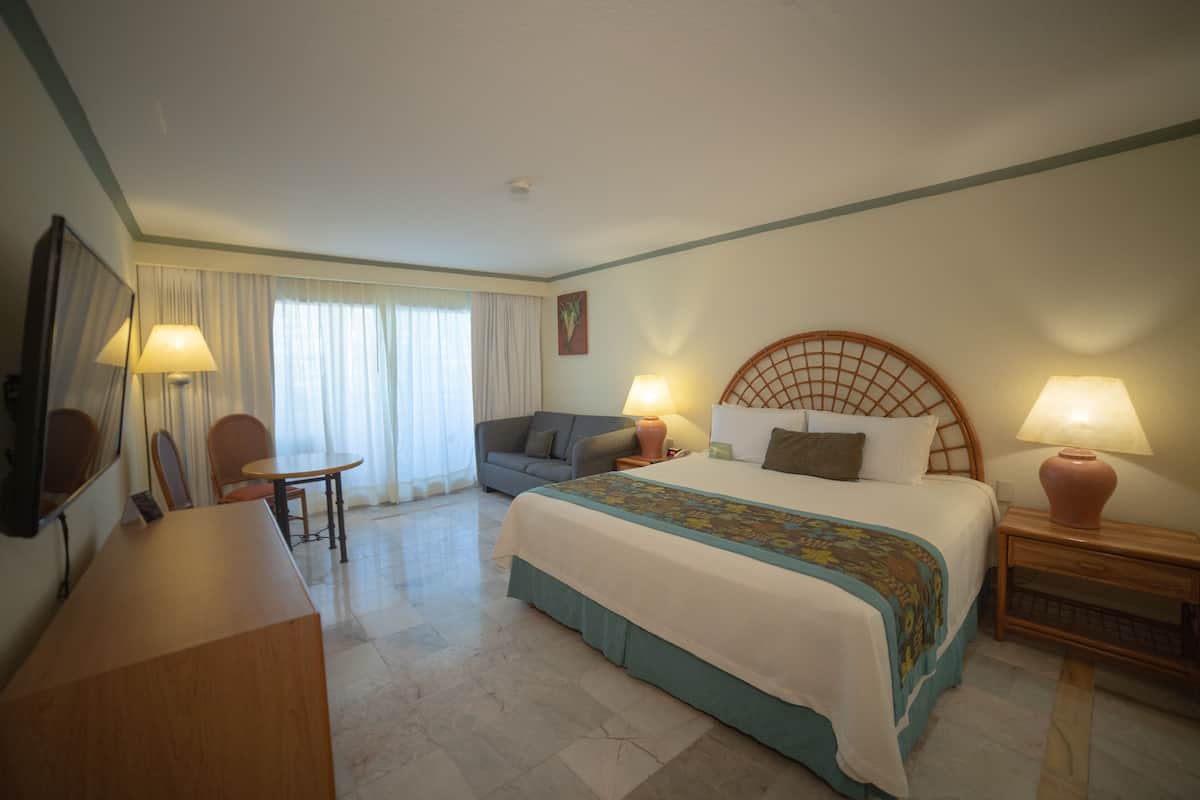 Una habitación de hotel con una cama, un escritorio, una silla, un sofá y una lámpara.