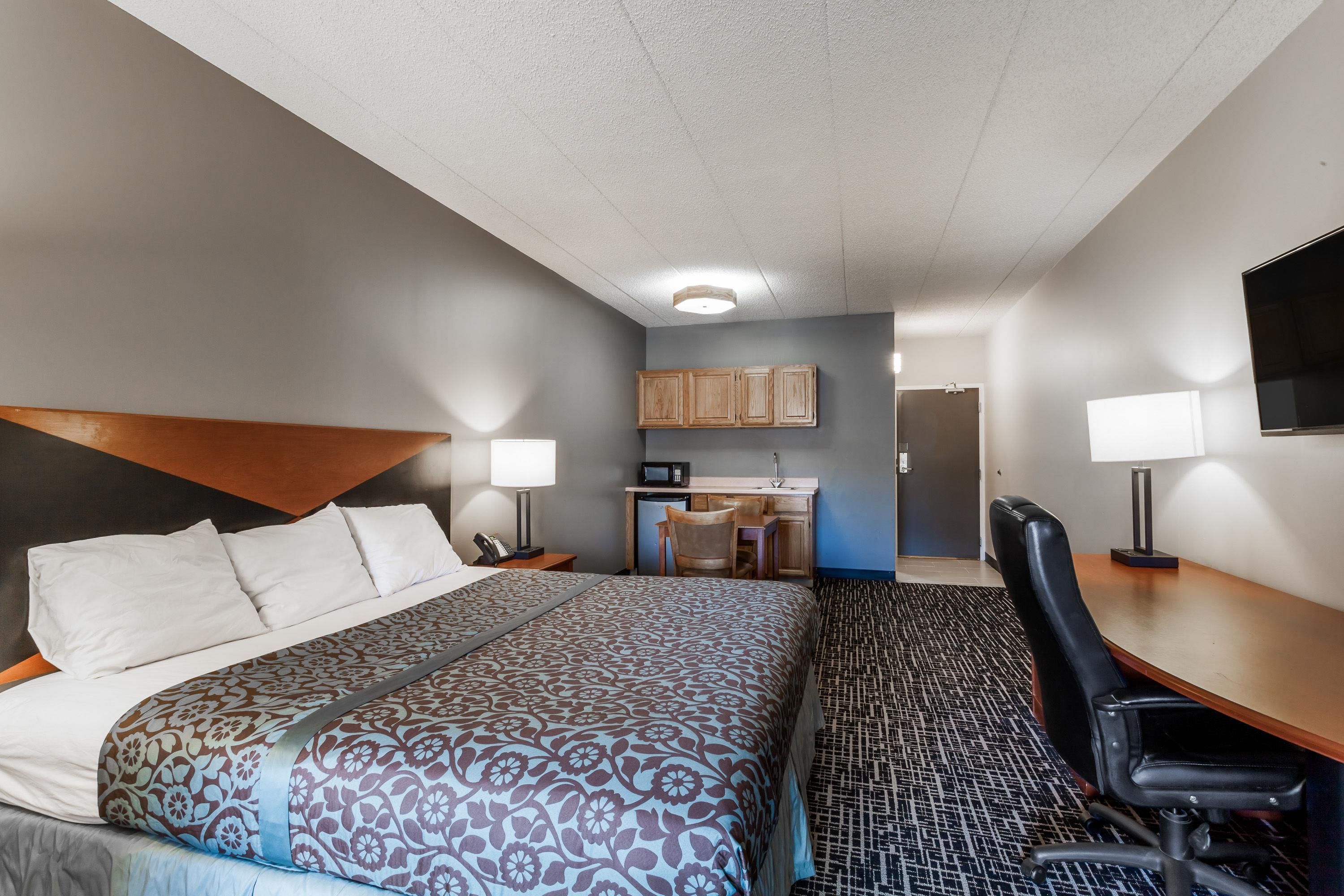 Ein Hotelzimmer mit Bett, Schreibtisch, Stuhl und Küchenzeile.