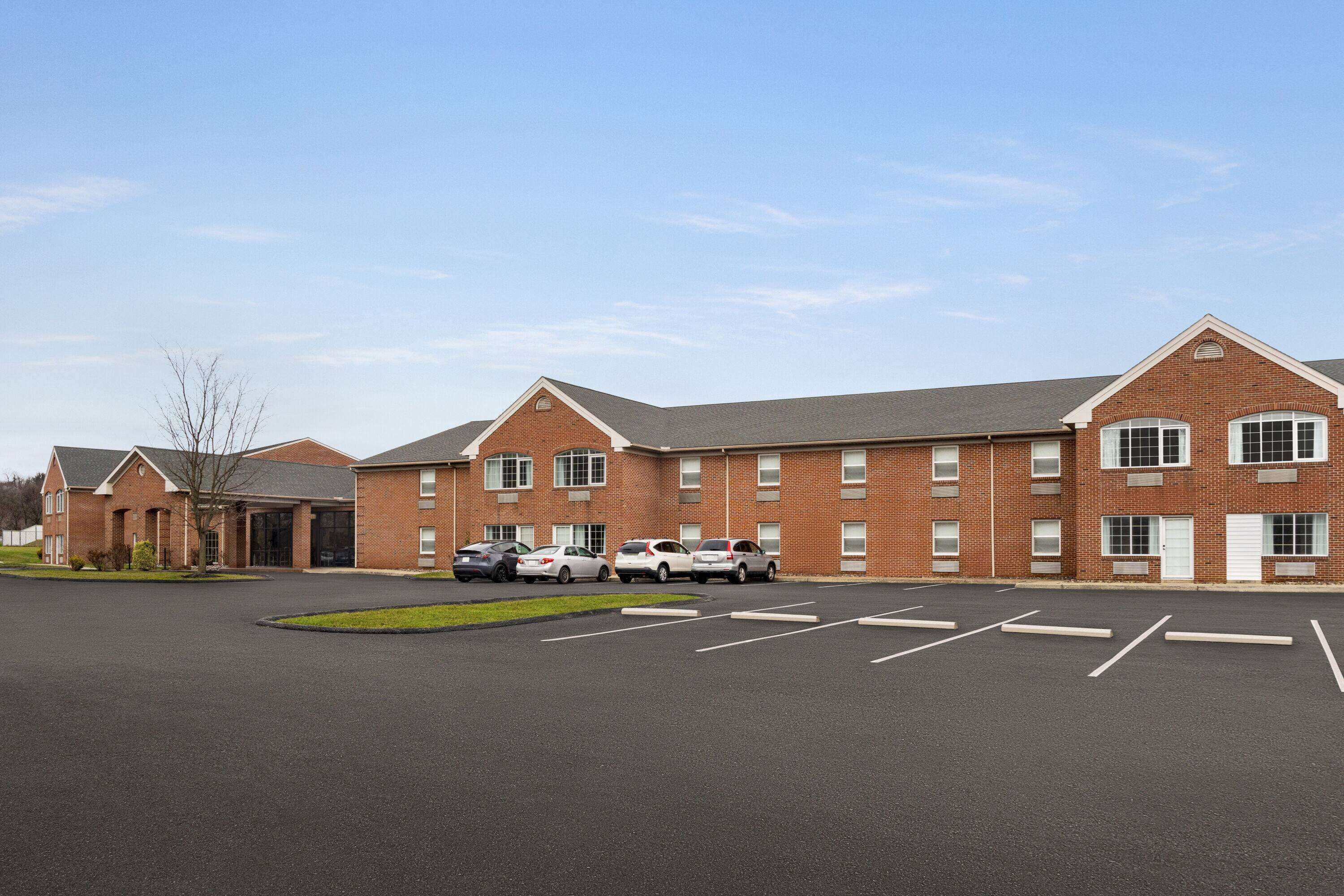 A multi-story brick building with a parking lot in front.