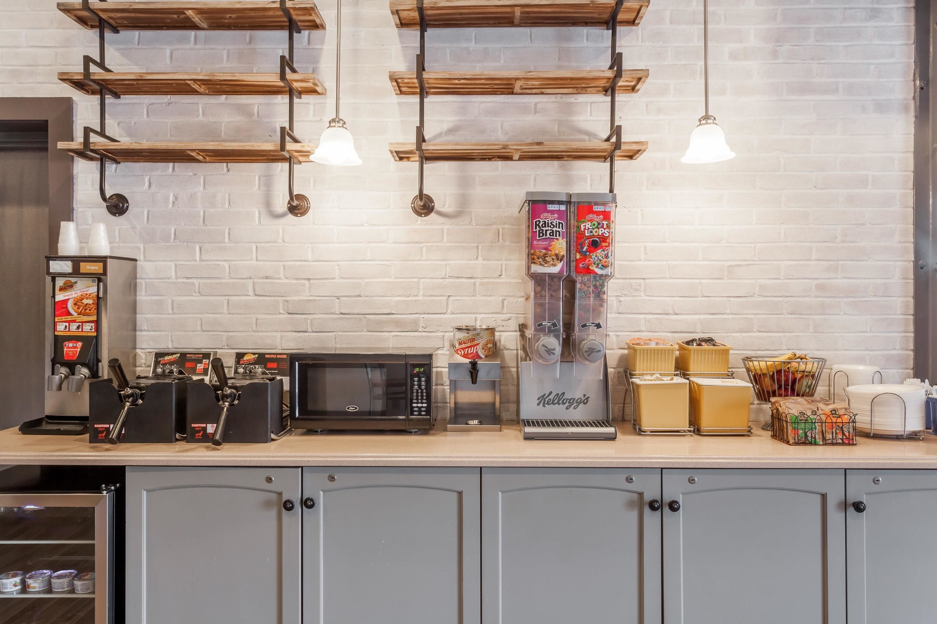 A coffee station with a microwave, coffee machines, and a refrigerator.
