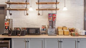 A coffee station with a microwave, coffee machines, and a refrigerator.