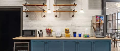 Una cocina con un armario azul, un microondas y varios utensilios de cocina sobre la encimera.