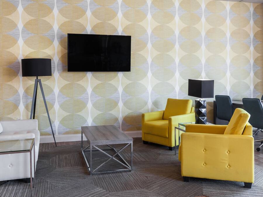 Ein modernes Wohnzimmer mit einer Couch, Sesseln, einem Couchtisch, einem Fernseher und einer Lampe.