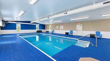 Una piscina con suelo de baldosas azules, rodeada de paredes en una combinación de colores azul y beige, y un techo con iluminación fluorescente.