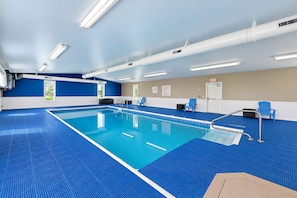 A swimming pool with a blue tiled floor, surrounded by walls with a blue and beige color scheme, and a ceiling with fluorescent lighting.
