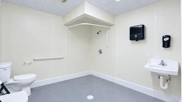 A bathroom with a toilet, a sink, a shower, and a hand sanitizer dispenser.