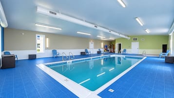 An indoor swimming pool with clear lanes, blue flooring, and overhead lighting.
