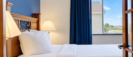 Habitación de hotel con cama, dos lámparas de noche, una ventana con vistas al exterior y una cortina.