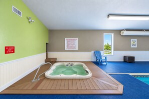 A hot tub in a room with a green wall, a window, and a chair. - Fairbridge Inn & Suites Williston Near Airport (Williston)