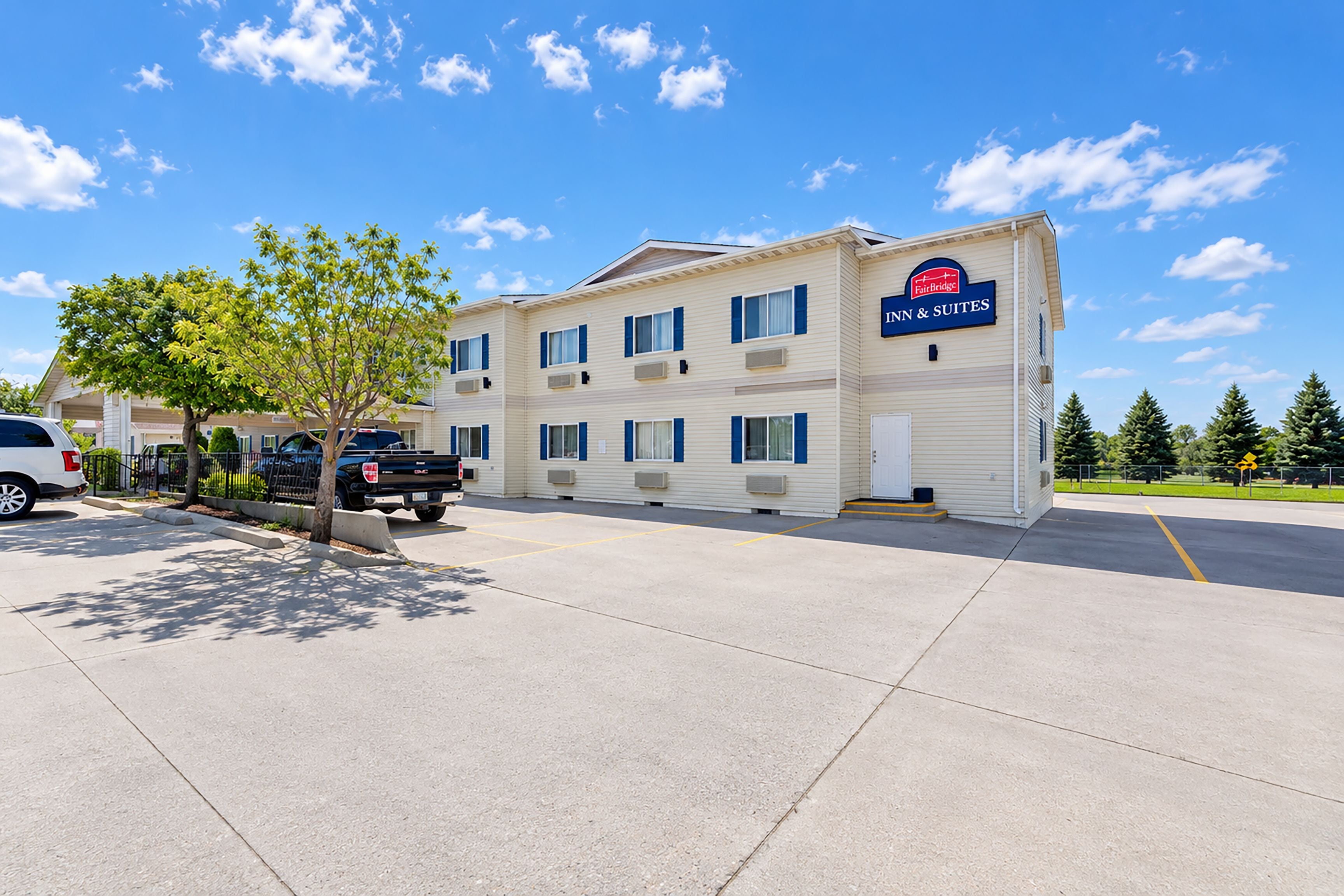 A two-story hotel with a sign for 'Inn & Suites' and a parking lot in front.