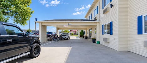 A motel with a covered parking area, a black pickup truck, and a row of parked motorcycles.