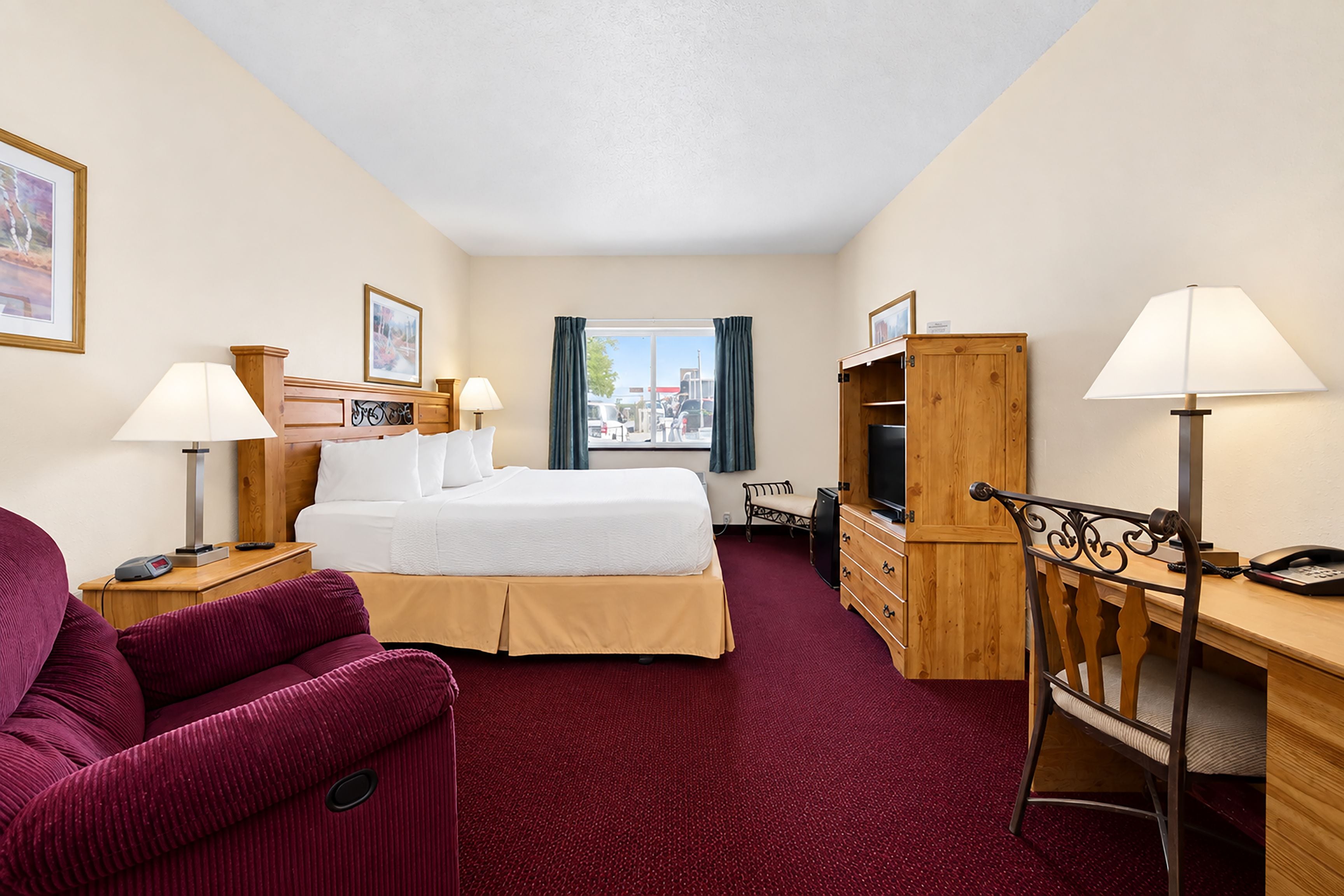 Ein Hotelzimmer mit einem Bett, einem Schreibtisch, einem Sessel, einem Fernseher und einem Fenster mit Blick nach draußen.