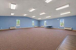 A spacious room with blue walls, a brown carpet, and multiple windows. - Fairbridge Inn & Suites Williston Near Airport (Williston)