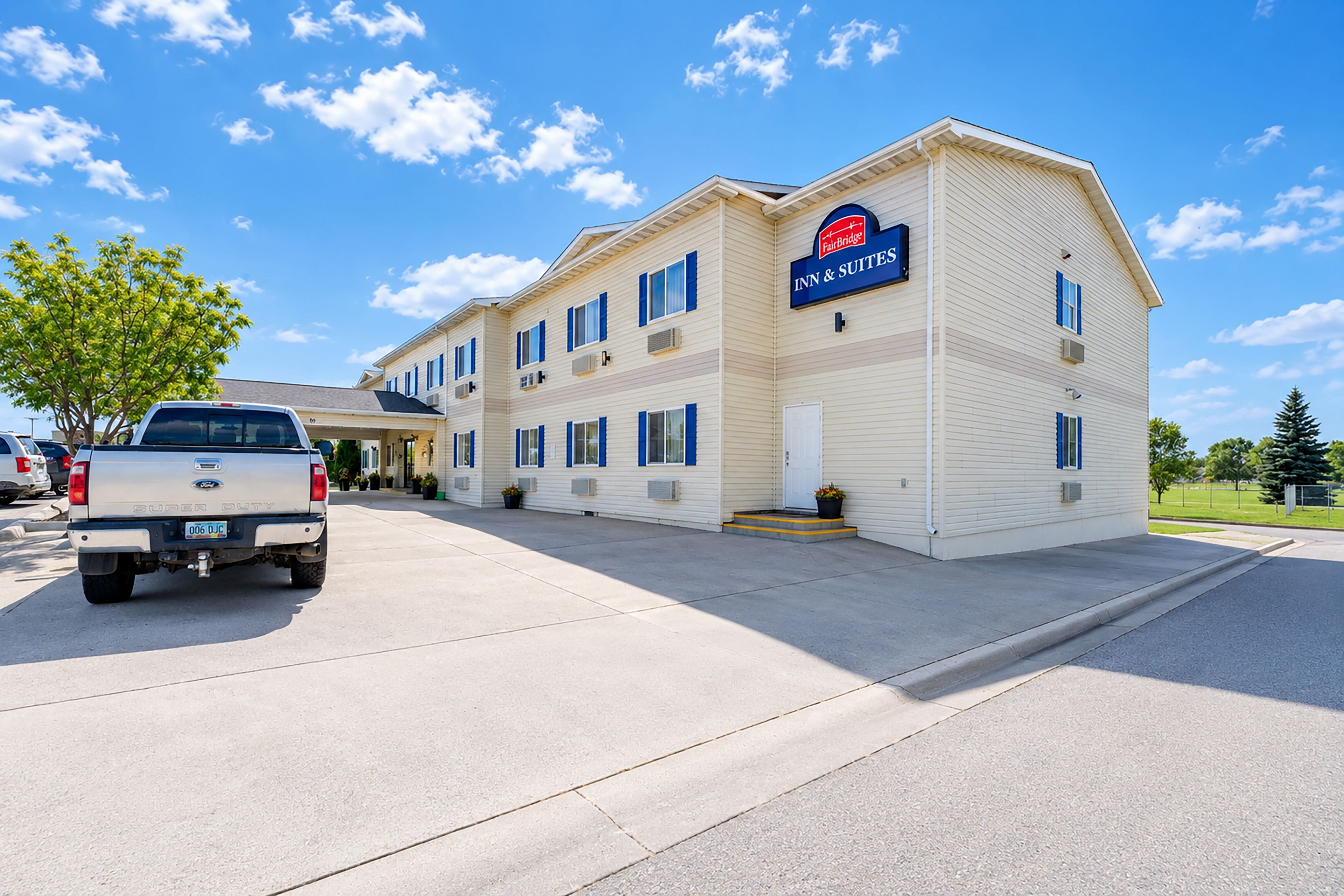 A two-story building with a sign for 'Fairbridge Inn & Suites.' There is a white pickup truck parked in front.
