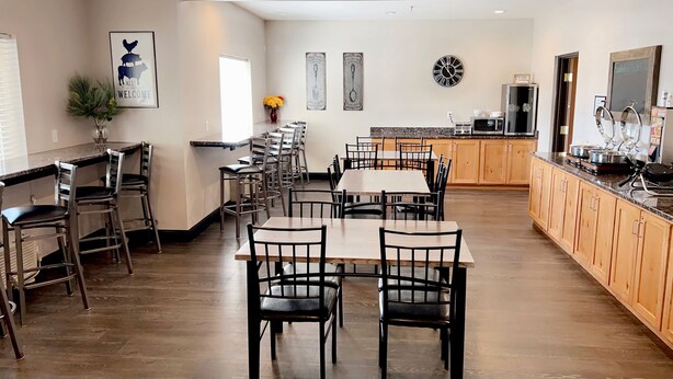 A spacious kitchen with wooden cabinets, a dining area with multiple tables and chairs, and a kitchen counter with appliances.