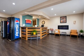 A hotel reception area with a Pepsi refrigerator, a clock, a television, and seating arrangements. - Fairbridge Inn & Suites Williston Near Airport (Williston)