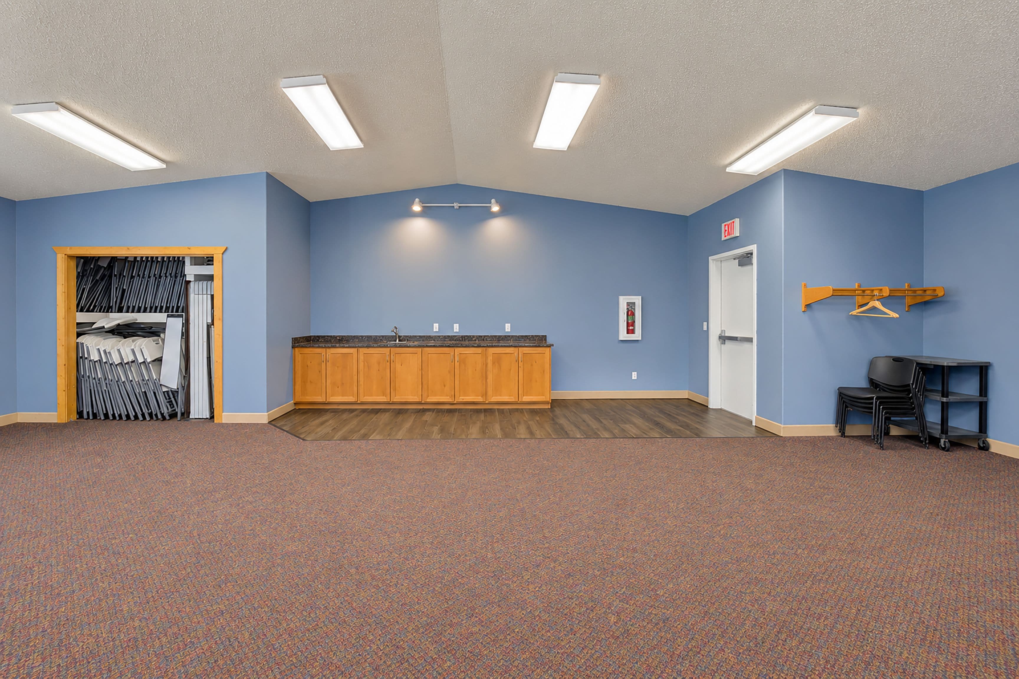 A room with a blue wall, wooden cabinets, a fire extinguisher, and a coat rack.