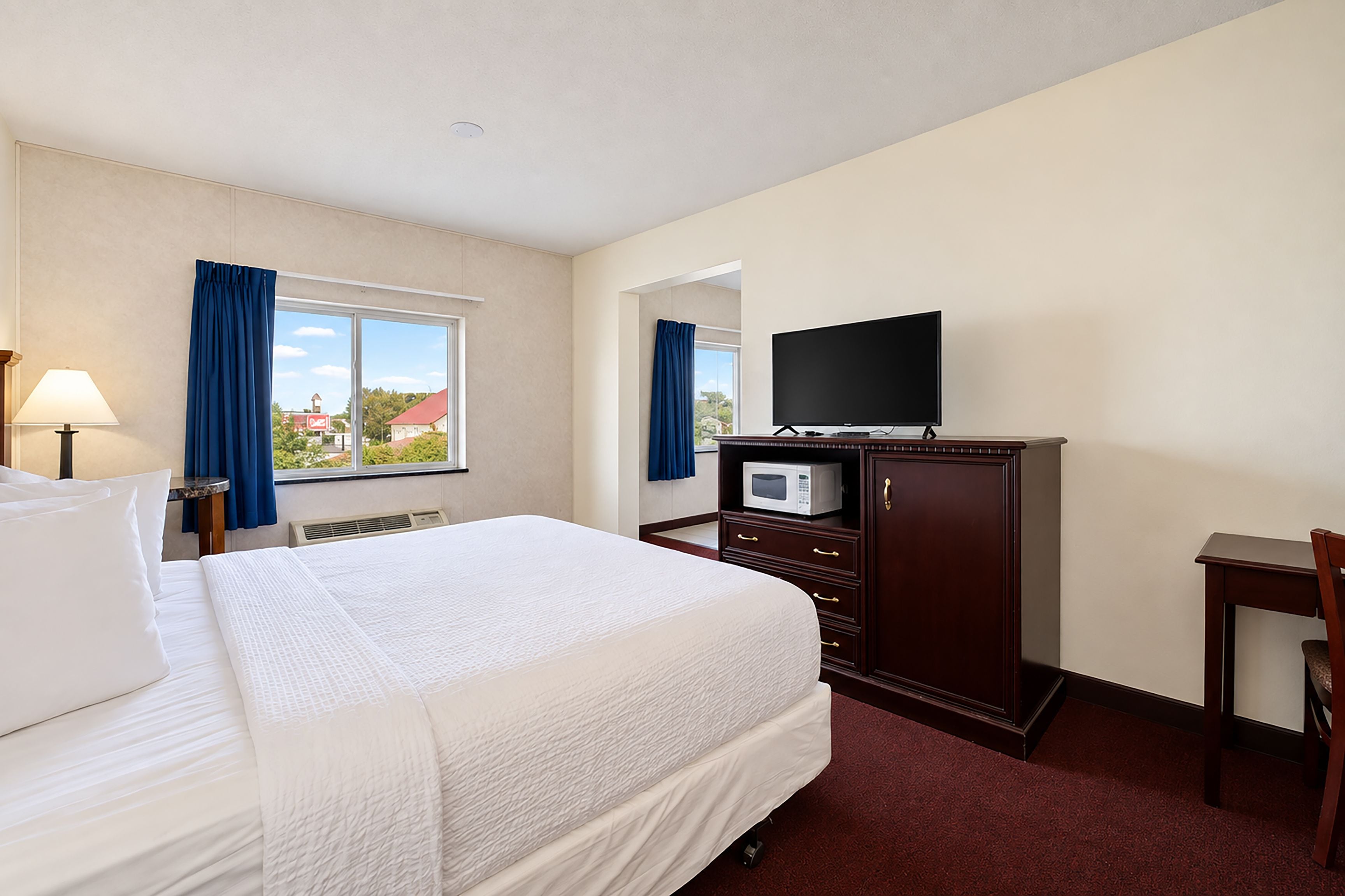 Ein Hotelzimmer mit einem Bett, einem Fernseher, einer Mikrowelle, einem Schreibtisch und einem Sessel.