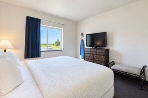 A hotel room with a bed, a television, a dresser, and a window with curtains. - Fairbridge Inn & Suites Williston Near Airport (Williston)