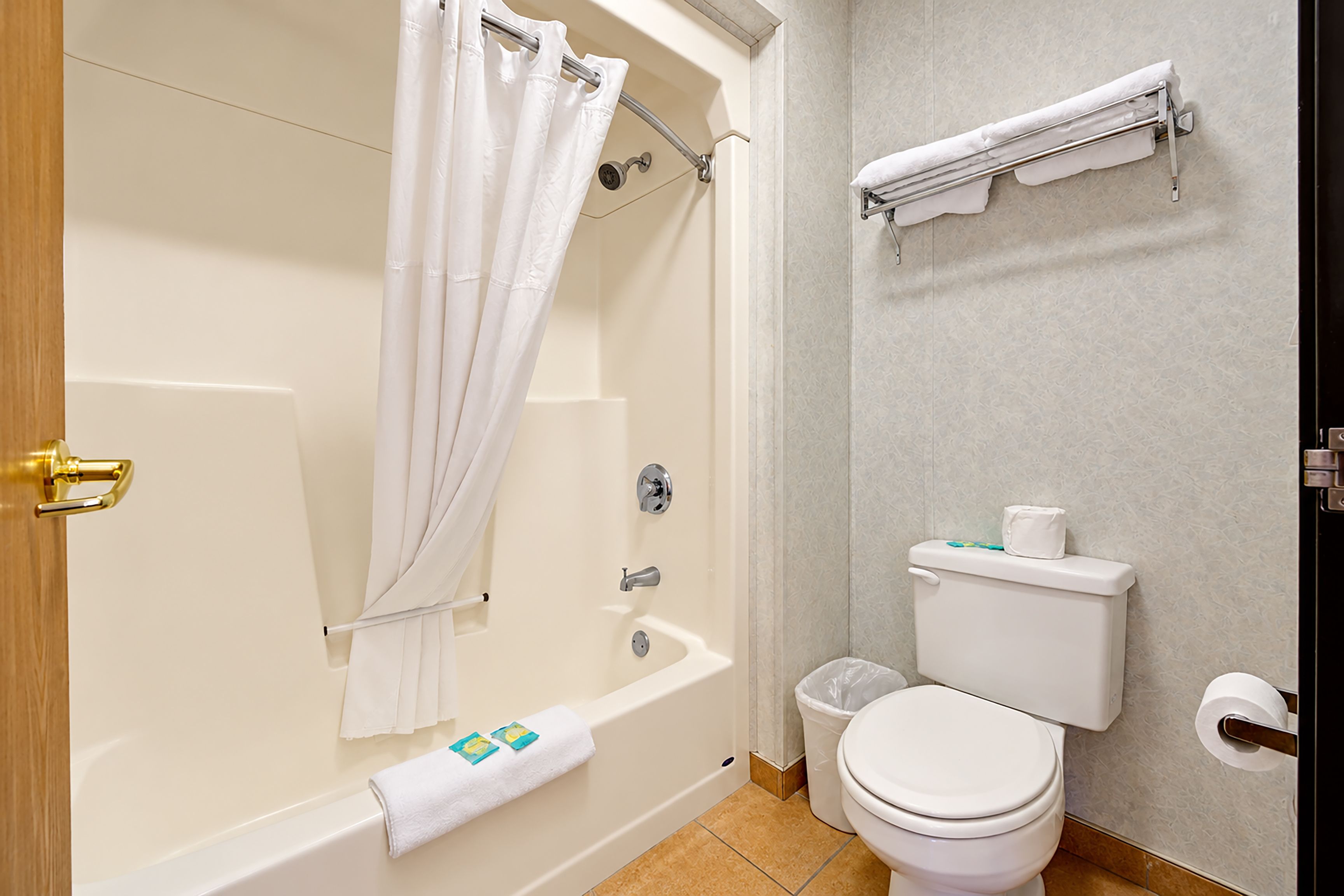 A bathroom with a bathtub, toilet, and a towel rack.