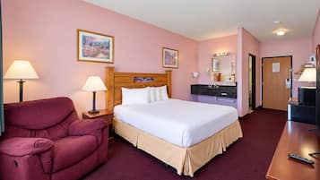A hotel room with a bed, a desk, a chair, a vanity, and a door.