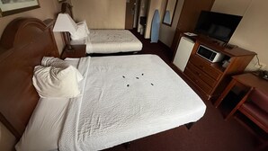 A hotel room with two beds, a television, a microwave, and a dresser.