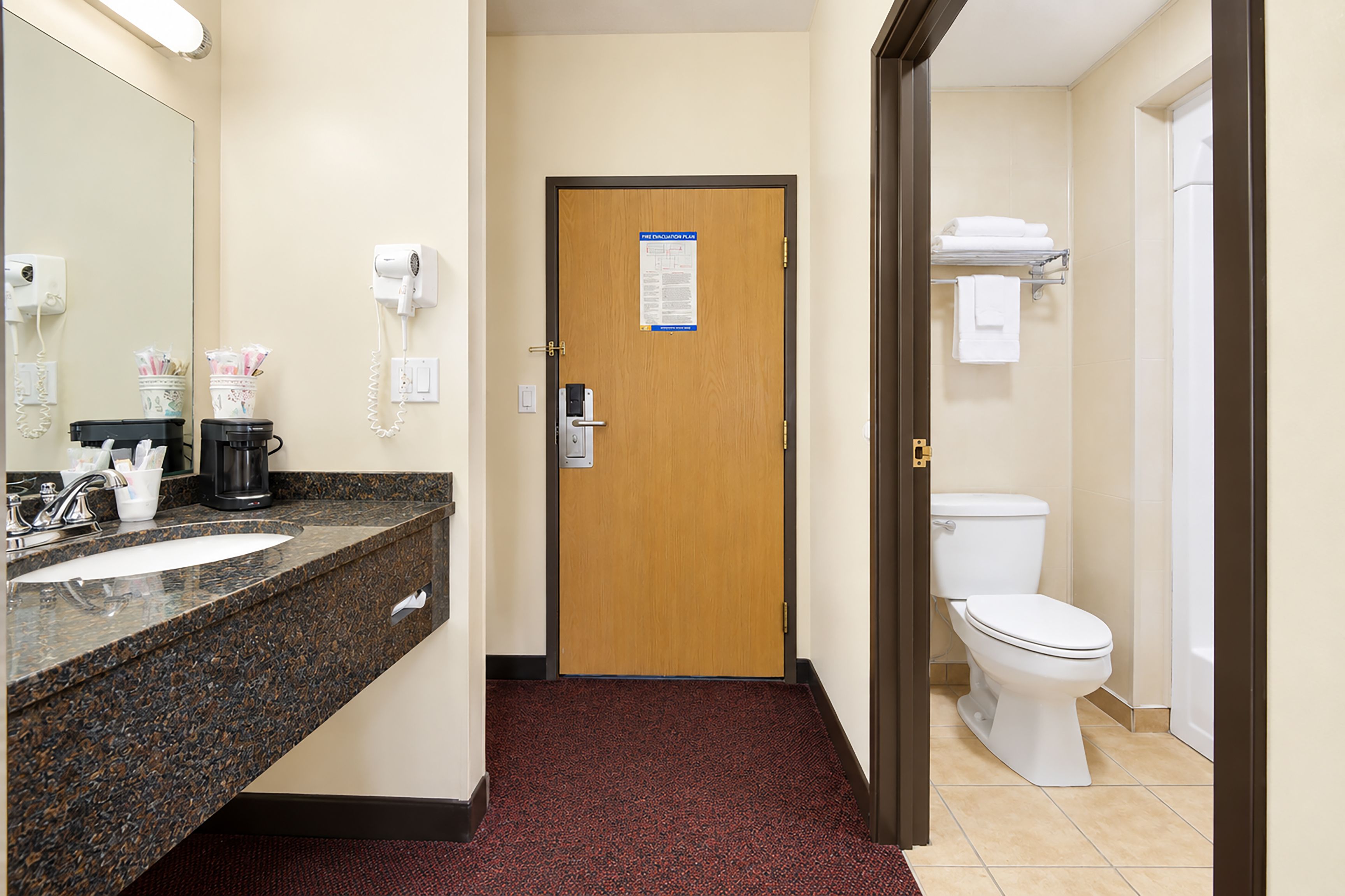 Ein Hotelbad mit Waschbecken, Spiegel, Handtuchhalter und Toilette.