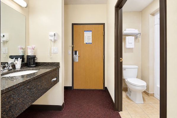 A hotel bathroom with a sink, mirror, towel rack, and toilet.