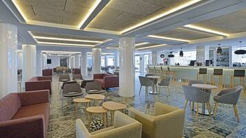 A spacious hotel lobby with modern seating, a bar area, and patterned flooring.
