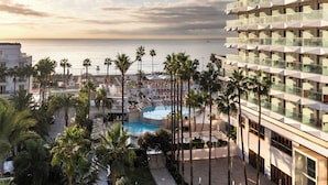 Un resort con piscina, palmeras y vista al mar.