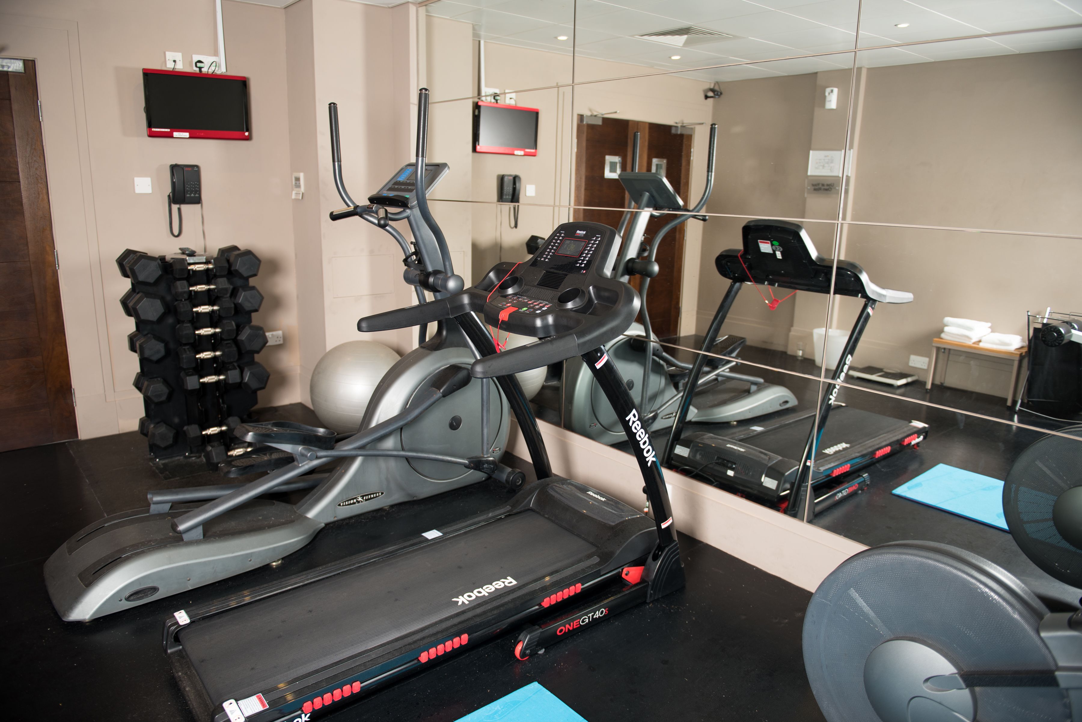 Un gimnasio con cintas de correr, elípticas y un banco de pesas.