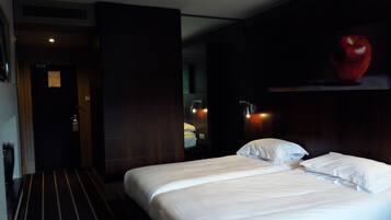 Una camera d'albergo con un letto grande, uno specchio e un'opera d'arte appesa al muro raffigurante una mela.