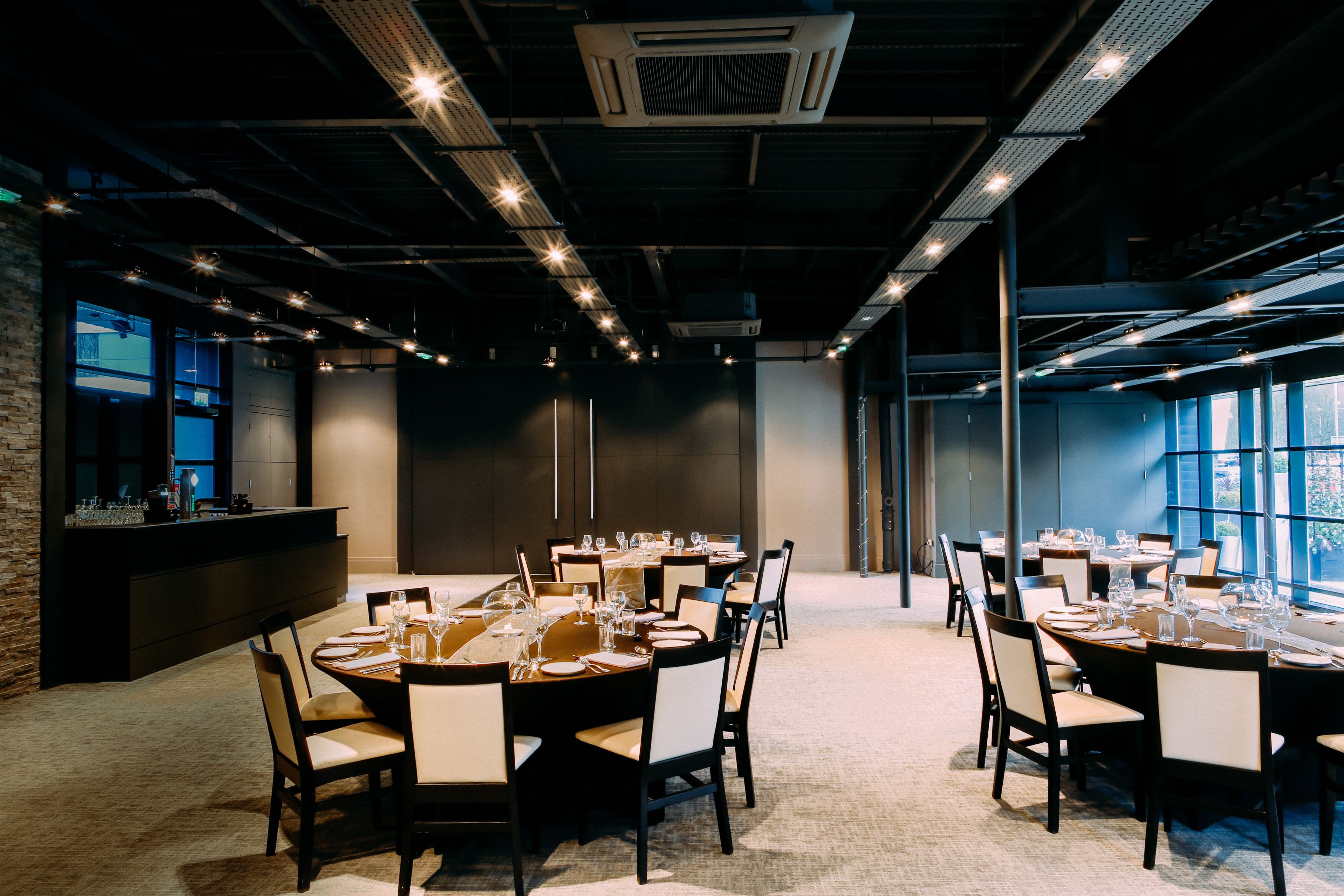A conference room with multiple tables set for dining, equipped with chairs and dining essentials.