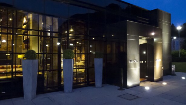 Un edifici modern amb grans finestres de vidre i una entrada ben il·luminada.